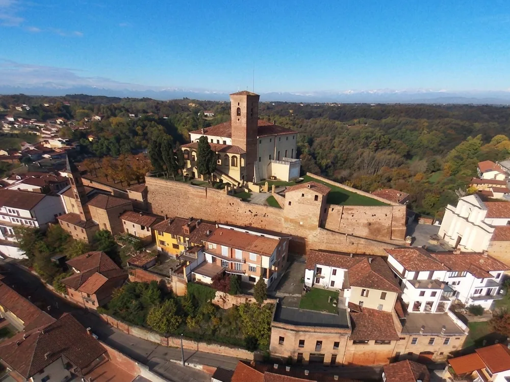 The medieval Castle of Cisterna d'Asti rising above the village rooftops in the Monferrato hills of Piedmont, with the Langhe countryside extending to the south