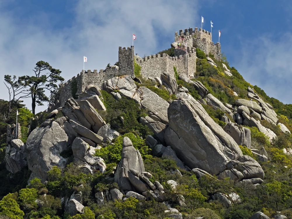Castle of the Moors ramparts on the Sintra ridge with Pena Palace visible behind and the Atlantic in the distance