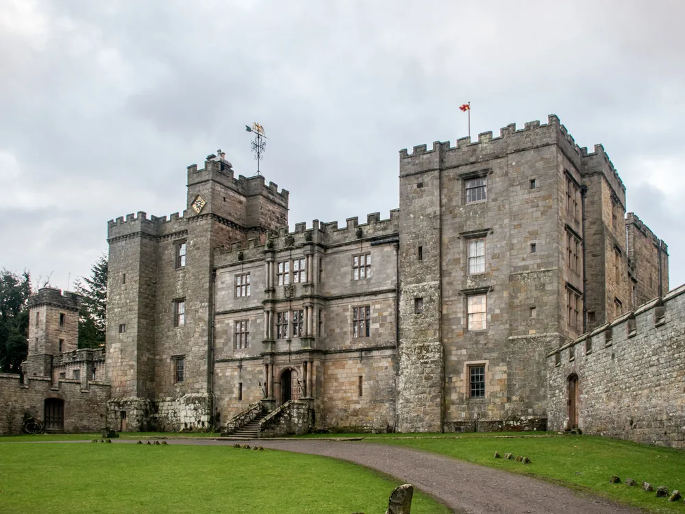 Chillingham Castle in Northumberland, England — the medieval Border fortress in the Till valley, now restored and operating as a heritage attraction with a ghost tour programme and the ancient wild white cattle herd in its surrounding park