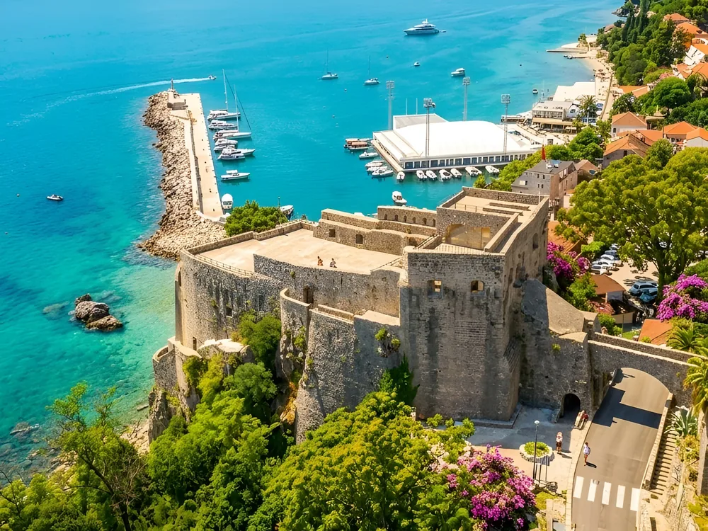 Forte Mare Fortress on its cliff above the Bay of Kotor in Herceg Novi, Montenegro — the 1382 Bosnian coastal fortress shaped by Ottoman and Venetian occupations, freely open at all times