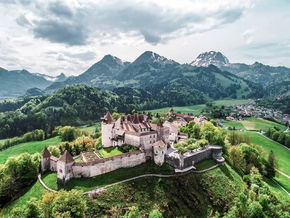 Gruyères Castle on its hilltop above the medieval village with the Fribourg Prealps in the background