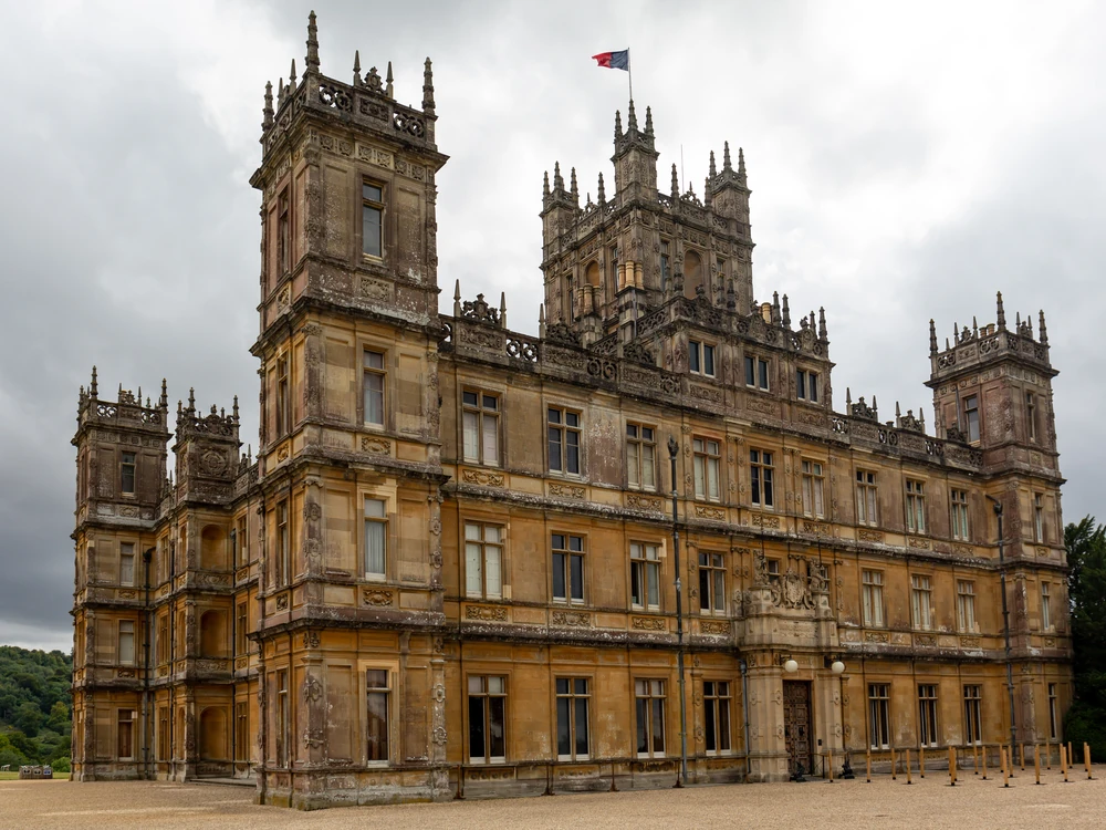 Highclere Castle's Victorian Gothic towers rising above landscaped lawns in Hampshire, instantly recognisable as the Downton Abbey country house