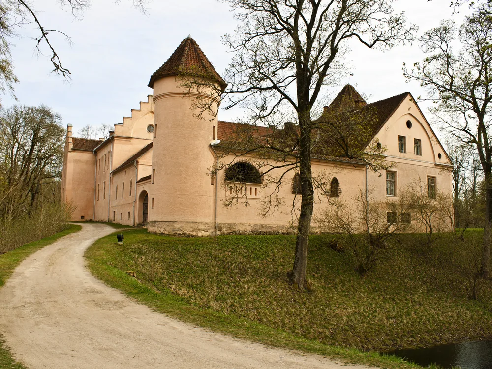 Jaunpils Castle (Jaunpils pils) in the Tukums district of Courland, Latvia — the intact 1301 Livonian Order tower house with corner turrets, now operating as a museum and medieval hotel in the western Latvian countryside