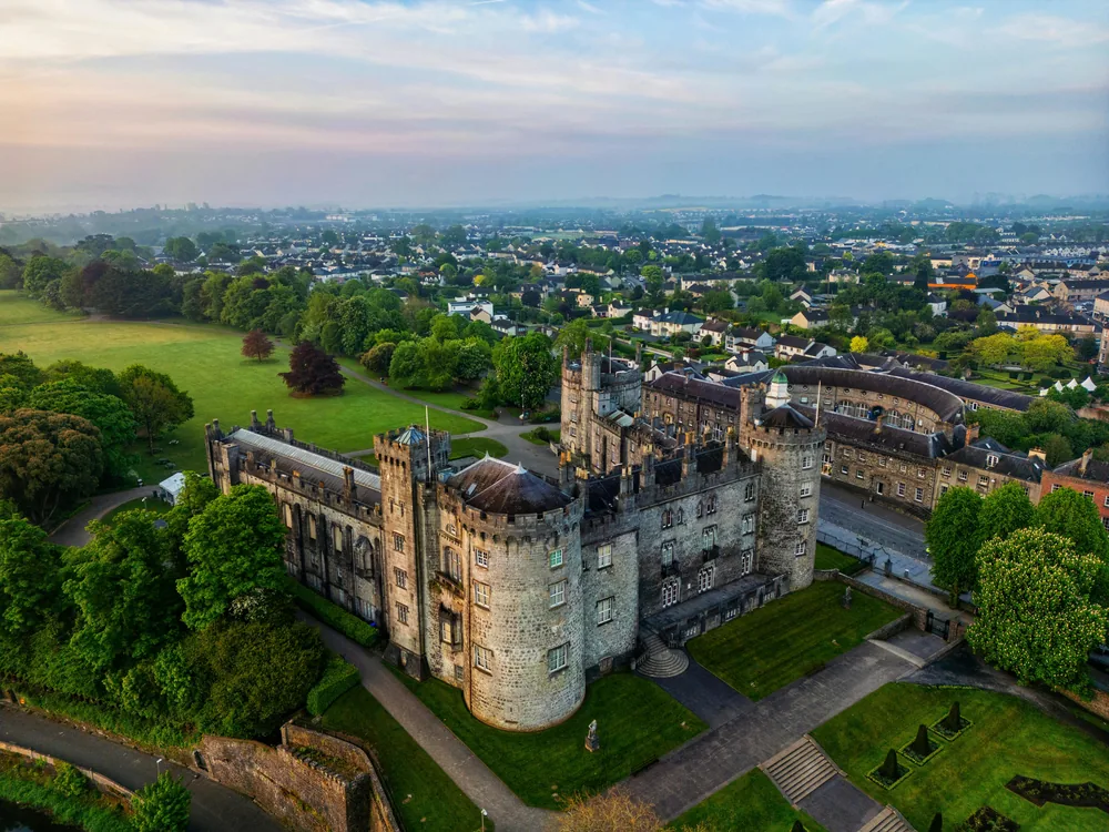 Kilkenny Castle above the River Nore with its three towers and parkland in early morning light