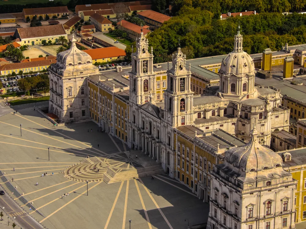 The colossal Baroque facade and twin bell towers of Mafra Palace in Portugal, stretching across the main square
