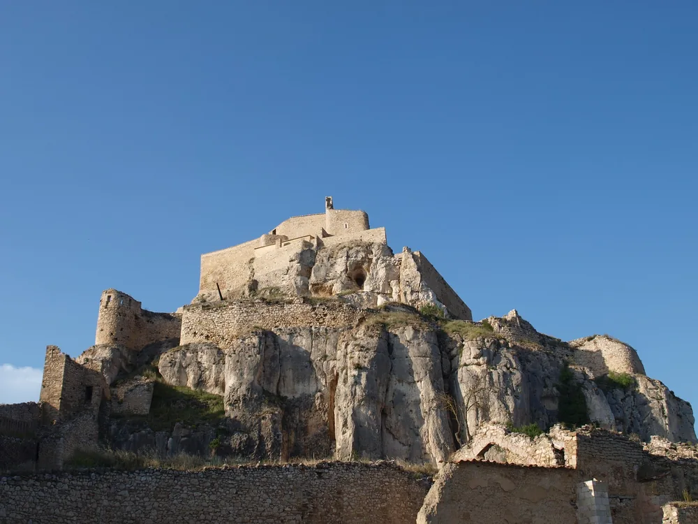 Morella Castle rising on its near-vertical limestone promontory above the intact medieval walled town, with the empty Maestrazgo plain stretching to the horizon