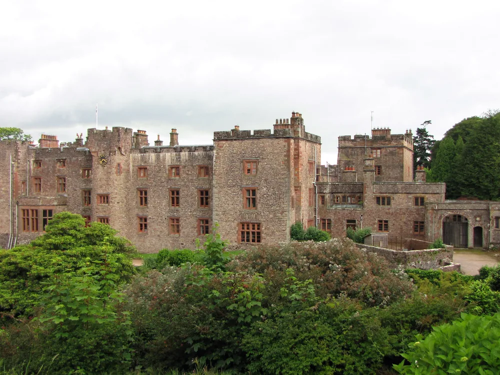 Muncaster Castle above the Esk valley in the western Lake District — the medieval peel tower and Victorian Gothic additions of the Pennington family's ancestral home, with 70 acres of Himalayan rhododendron gardens