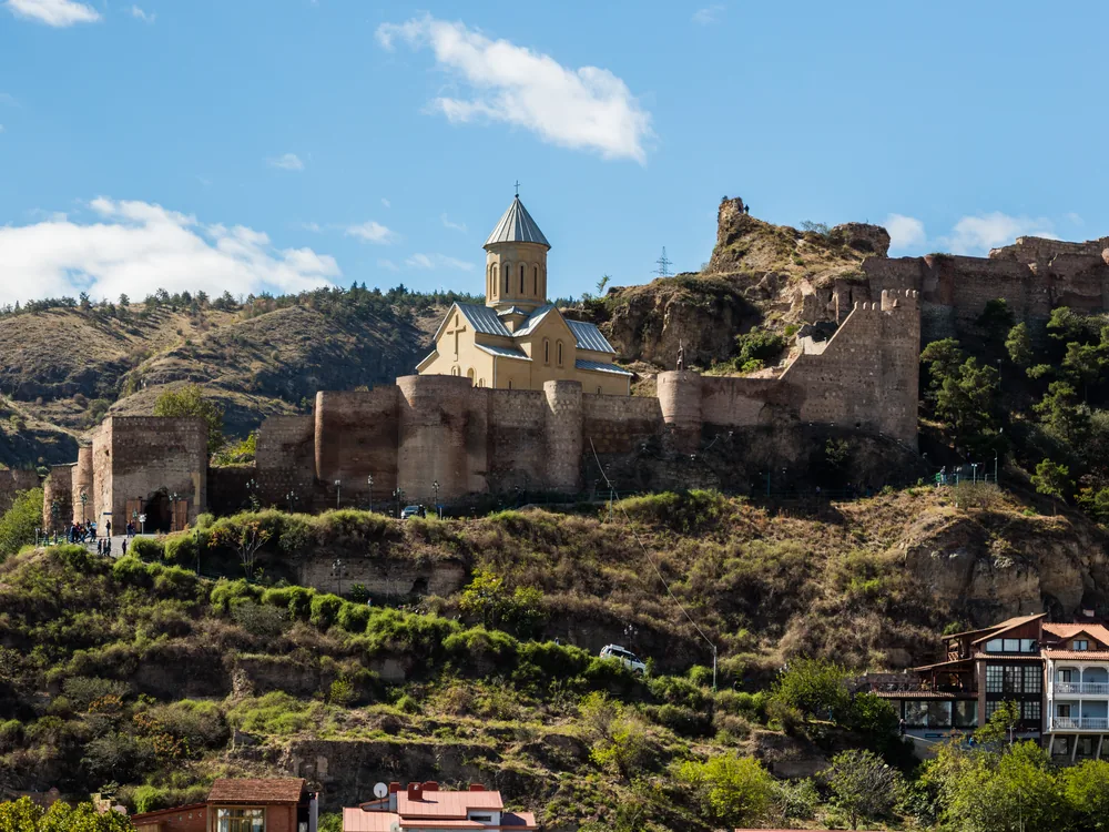 Narikala Fortress above Tbilisi's Old Town — the 1,600-year-old hilltop citadel on the Sololaki ridge, with the Kartlis Deda (Mother of Georgia) monument on the adjacent hill and the Mtkvari River below