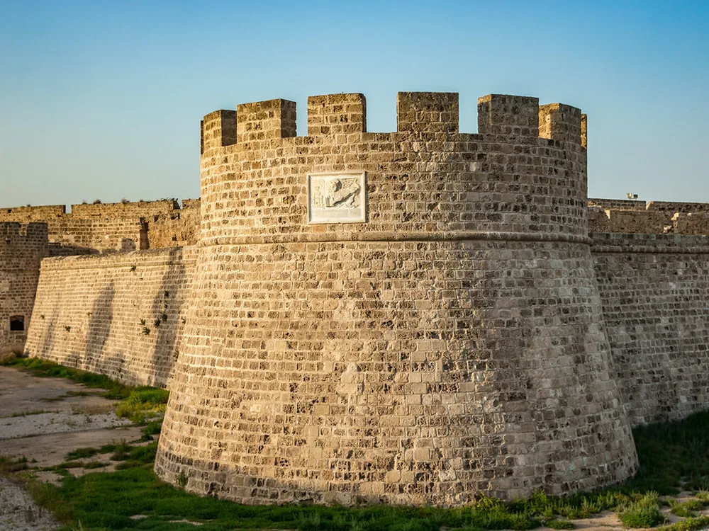 Othello Castle — the Lusignan sea-gate fortress in the walled city of Famagusta, Northern Cyprus, with the Lion of St Mark Venetian relief above the main entrance and the rounded artillery-era towers rebuilt in 1492