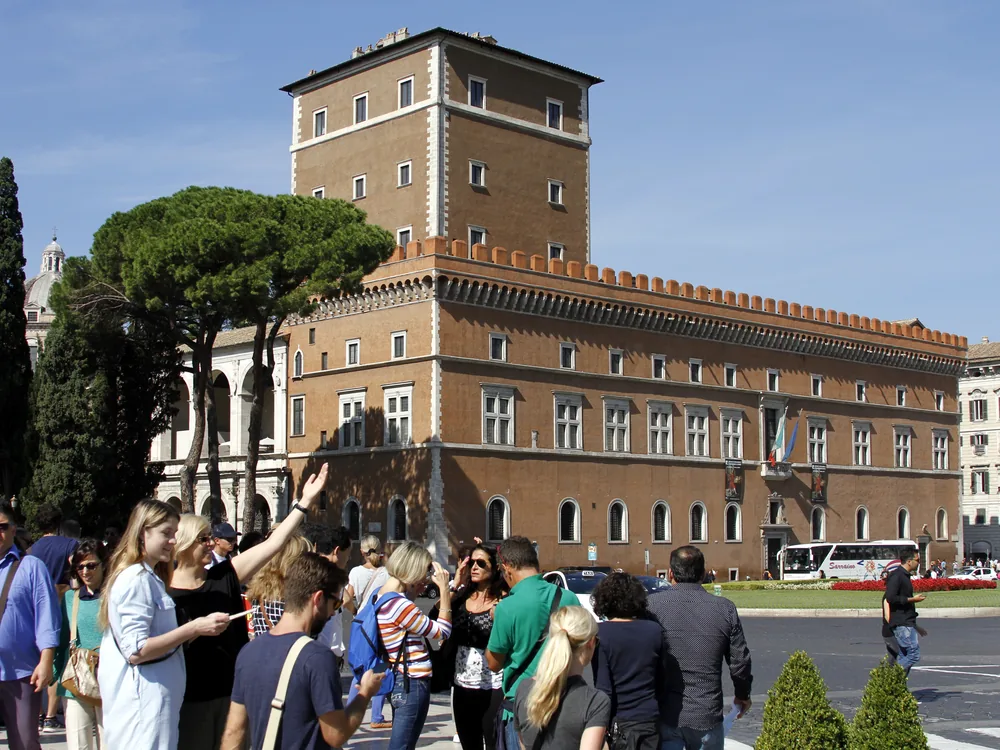 Palazzo Venezia on Piazza Venezia in Rome — the 15th-century papal palace and Mussolini's seat of government, with the Vittoriano Monument adjacent and the Capitoline Hill behind