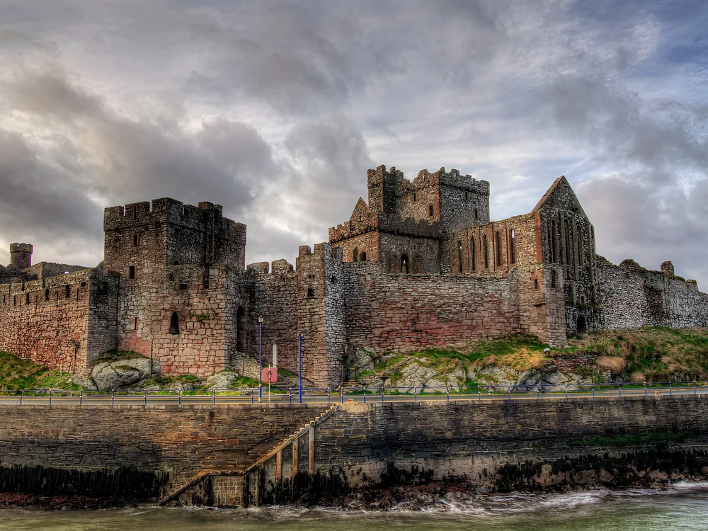 Peel Castle on St Patrick's Isle in Peel Harbour, Isle of Man — the red sandstone curtain walls, Round Tower, and ruined Cathedral of St German above the Irish Sea