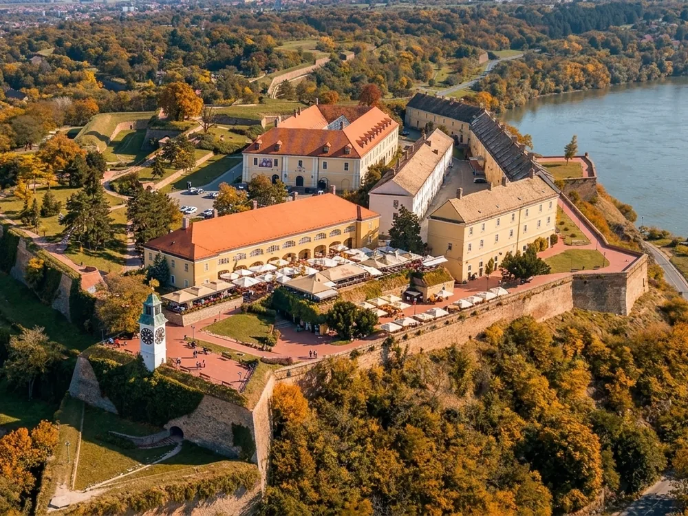 Petrovaradin Fortress on the loess bluff above the Danube at Novi Sad, Serbia — the 18th-century Habsburg fortress known as Gibraltar on the Danube, with the clock tower's reversed hands visible from the river