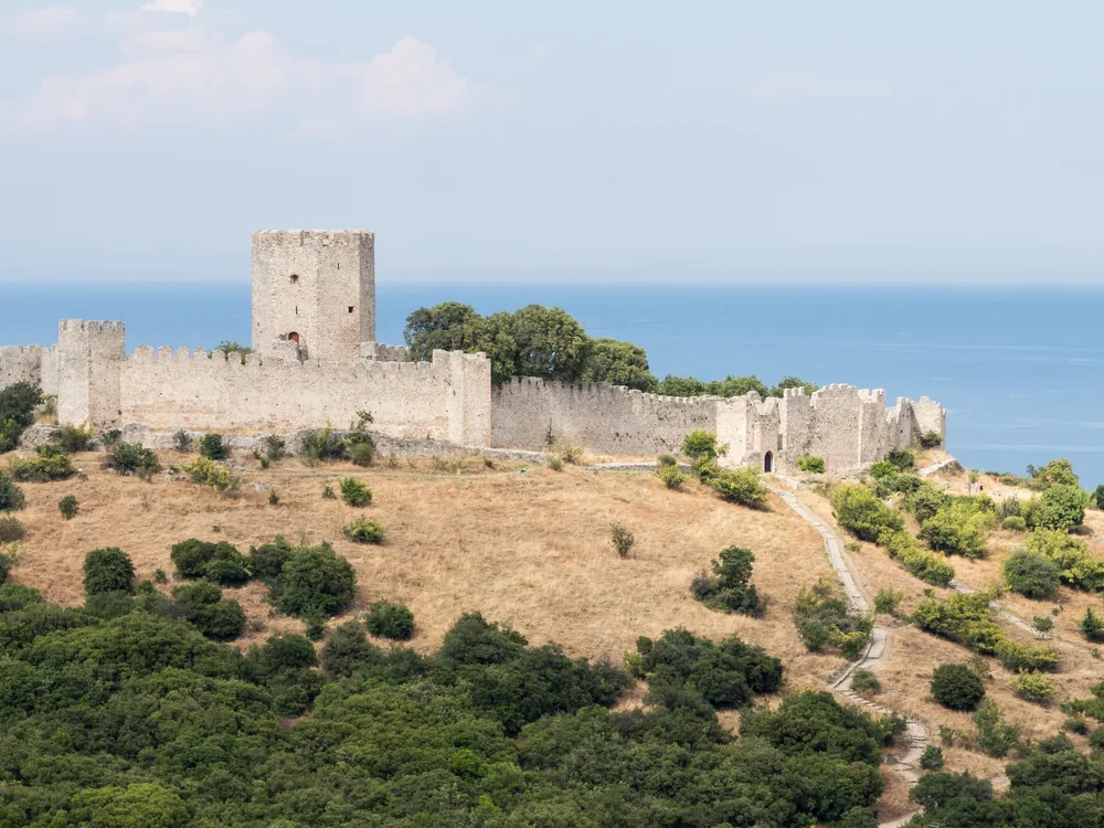 Platamon Castle on its Aegean promontory with Mount Olympus visible in the background — the Crusader fortress guarding the gateway between Macedonia and Greece