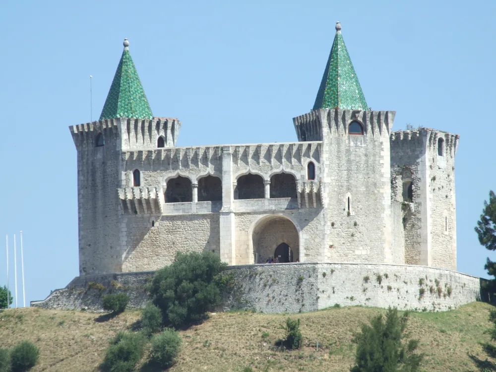 Porto de Mós Castle (Castelo de Porto de Mós) above the town of Porto de Mós, Leiria District, Portugal — the distinctive conical green-tiled tower roofs of the 15th-century Gothic-Manueline reconstruction, with the limestone hills of the Serra de Aire e Candeeiros behind