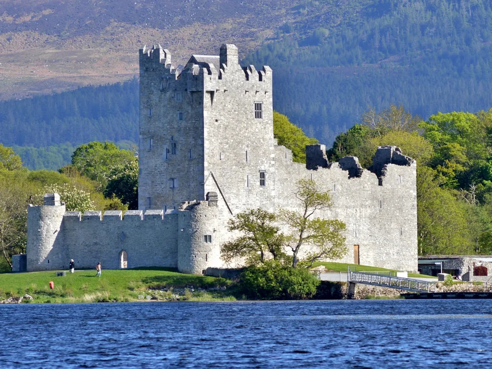 Ross Castle on the shore of Lough Leane in Killarney National Park — the 15th-century O'Donoghue Mór tower house with the MacGillycuddy's Reeks reflected in the water