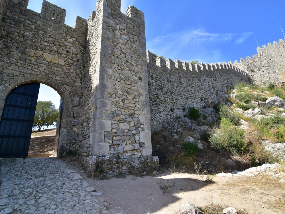 Sesimbra Castle (Castelo de Sesimbra) on the hilltop above the Arrábida coast and the Atlantic — the Moorish-Portuguese medieval castle with panoramic views over the fishing town of Sesimbra and the Serra da Arrábida, Setúbal District, Portugal