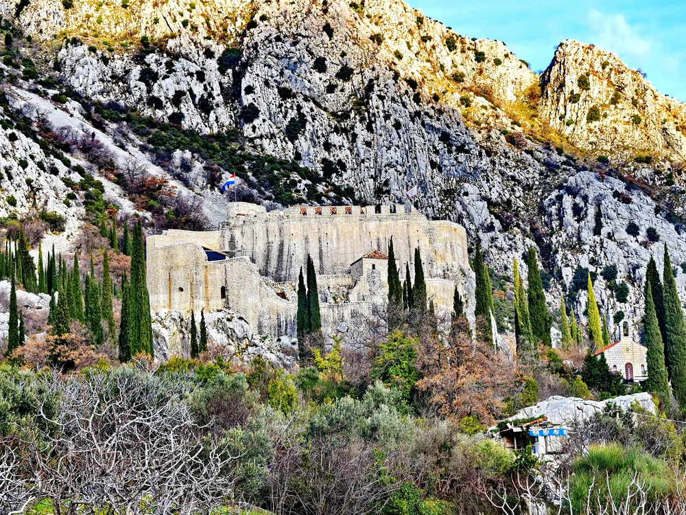 Sokol Fortress (Sokol Grad) on a karst cliff above the Konavle Valley near Dubrovnik, Croatia — the medieval Ragusan fortress whose name means 'falcon,' overlooking the agricultural valley that was one of the Dubrovnik Republic's most valued territories