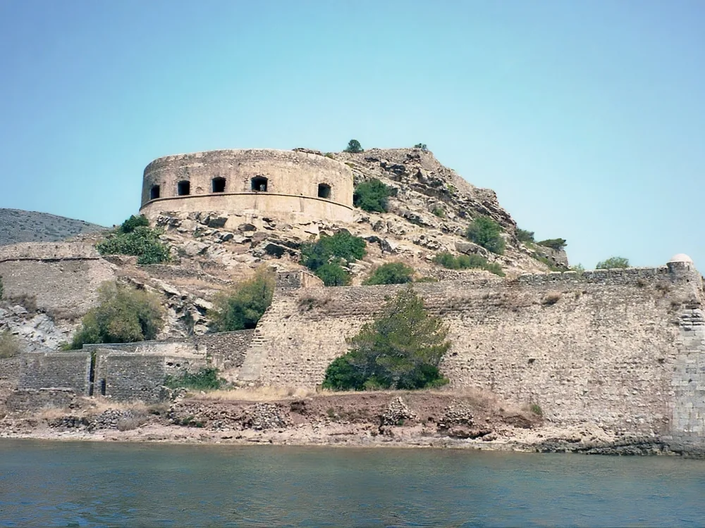 Spinalonga Island Fortress in the Gulf of Elounda, Crete, Greece — the 1579 Venetian fortress turned leper colony, viewed from the water with its massive bastions rising above the turquoise Aegean