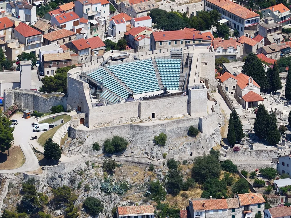 St. Michael's Fortress (Tvrđava Sv. Mihovila) — the medieval Croatian fortress above the harbor entrance in Šibenik, with the dome of the UNESCO Cathedral of St. James visible below, Croatia