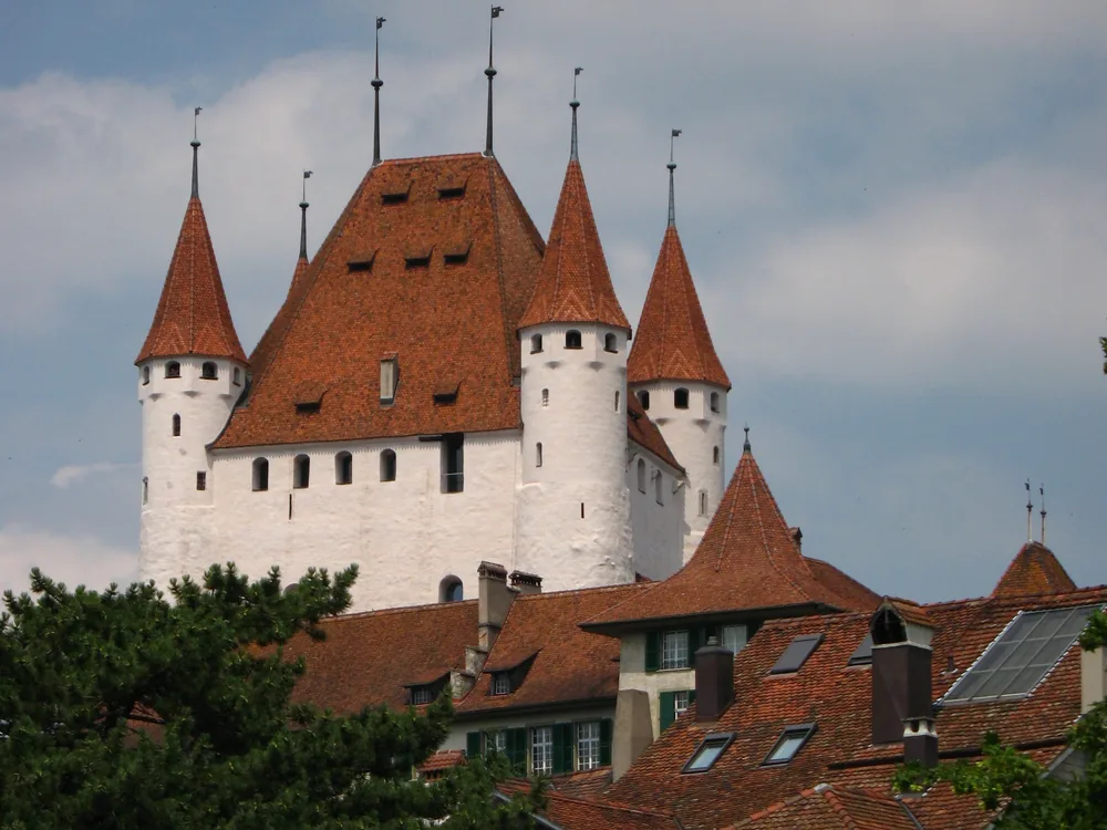Thun Castle (Schloss Thun) above Thun's medieval old town, with the Aare river and Lake Thun visible beyond — the 12th-century Zähringen keep that has defined the Thun skyline for over 800 years