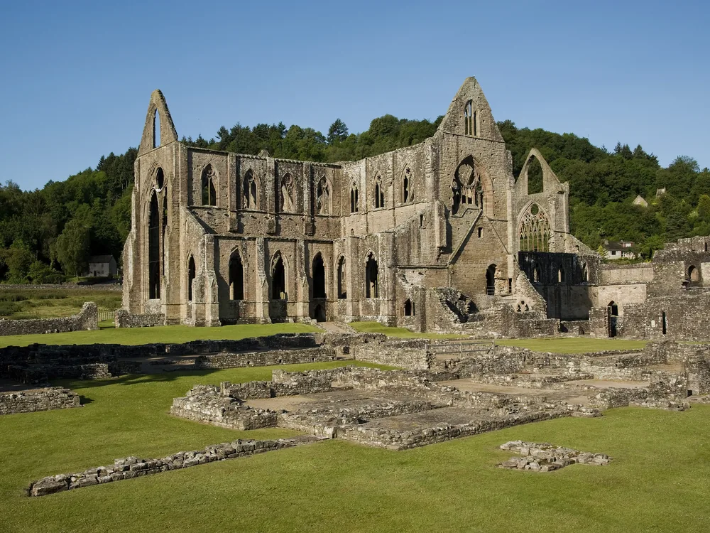 Tintern Abbey in the Wye Valley — the roofless Gothic nave and window tracery of the Cistercian ruin at dusk