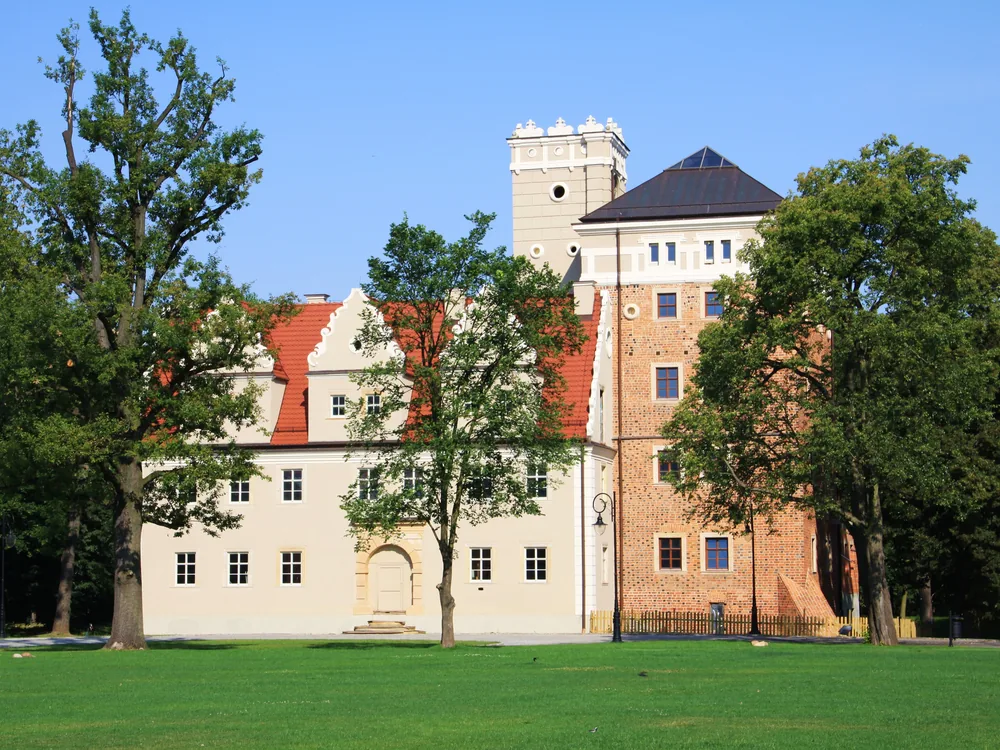 Topacz Castle at Ślęza on the southern edge of Wrocław, Poland — a medieval moated tower beside an 18th-century manor, now a hotel and motor museum