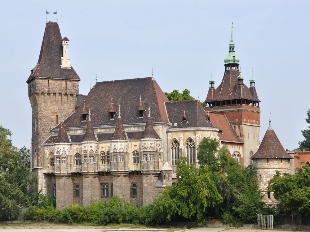 Vajdahunyad Castle's eclectic towers reflected in the pond of City Park, Budapest