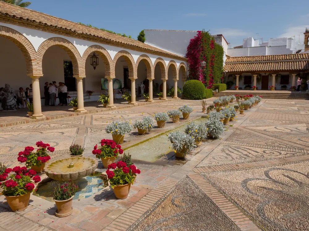 Palacio de Viana in Córdoba — one of the 12 Andalusian courtyards of the palace, with whitewashed walls, wrought-iron rejas, and geranium-covered columns in the Córdoba patio tradition