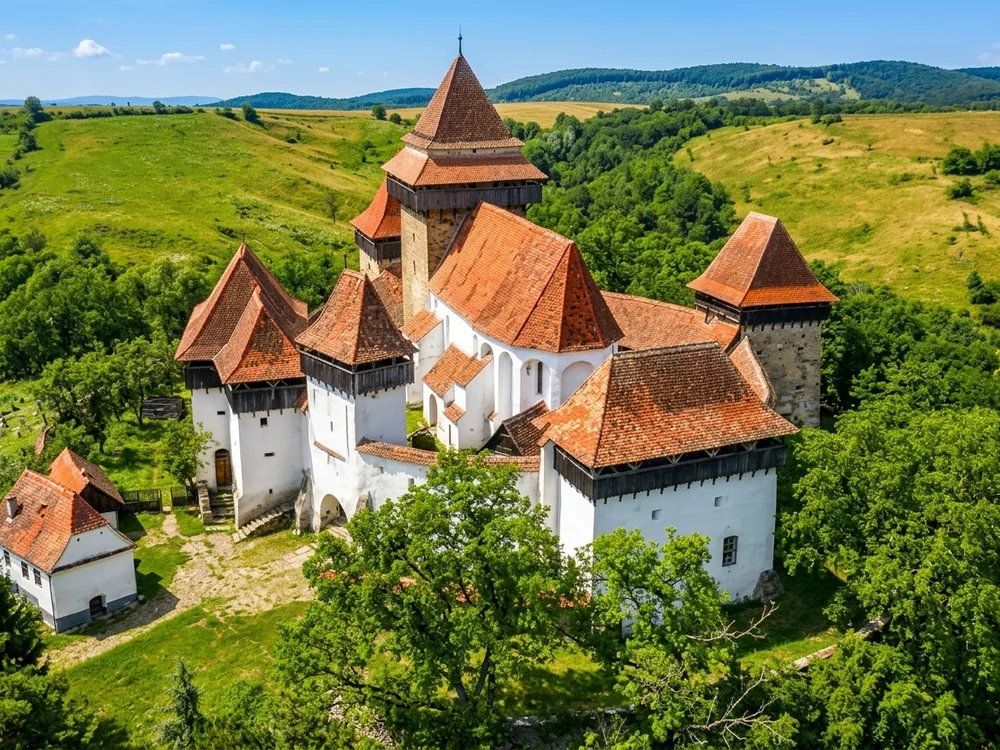 Viscri Fortified Church (Weißkirch / Viscri) in Brașov County, Transylvania, Romania — the UNESCO-listed 12th-century Saxon Romanesque church within its circular defensive walls above the village street