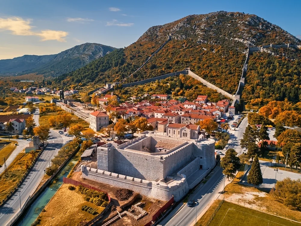 The medieval Walls of Ston stretching across the Pelješac Peninsula in Croatia — the 14th-century Ragusan fortification system with towers and crenellated parapets overlooking the Ston saltworks and the Adriatic