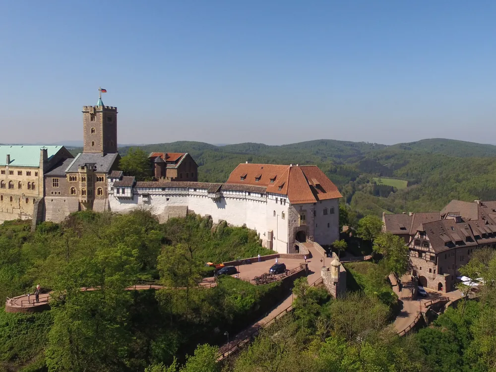 Wartburg Castle above the autumn forest of Thuringia, its red roofs visible above the beech trees