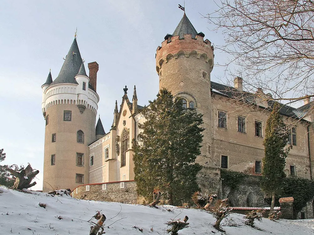 Žleby Castle (Zámek Žleby) in Central Bohemia — the Auersperg family's 19th-century Romantic neo-Gothic château with pointed turrets and battlements, reflected in the landscape park, Czech Republic