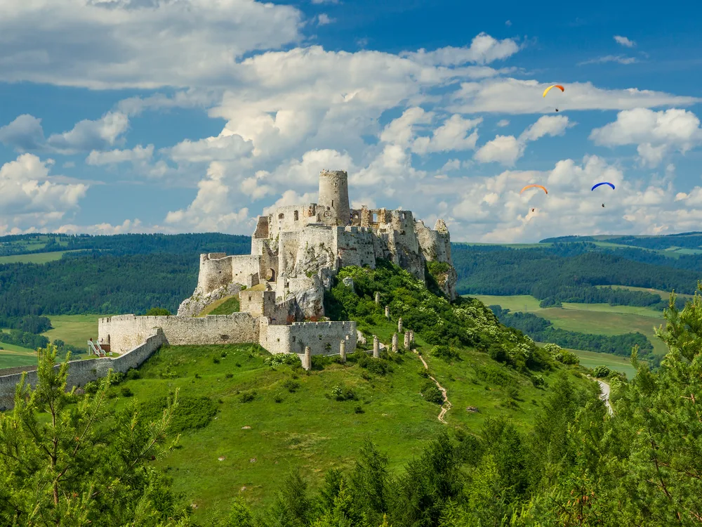 Spiš Castle ruins on their dolomite crag above the Spiš plain, with the High Tatra Mountains visible on the horizon