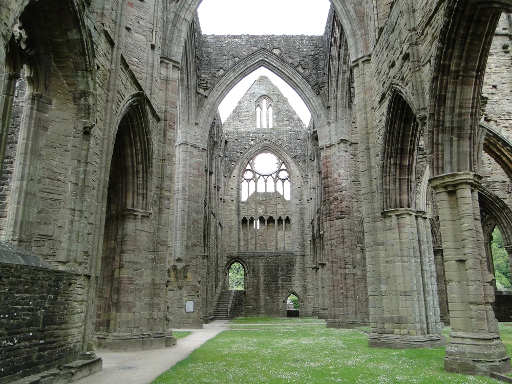 Tintern Abbey's Gothic nave walls and great east window rising above the Wye Valley — the centrepiece of the Cardiff Caerleon and Three Castles tour