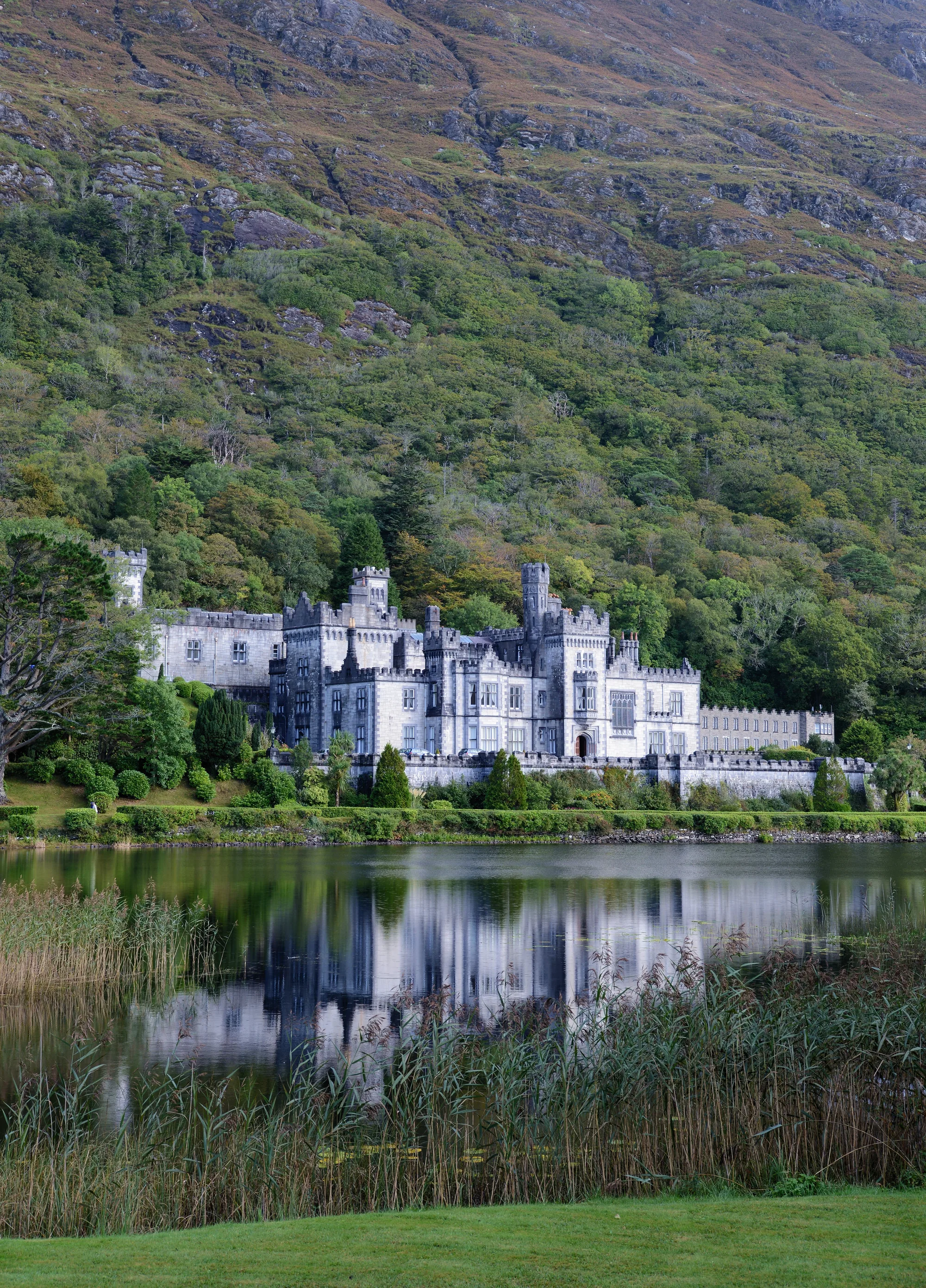 Kylemore Abbey reflected in the still waters of Kylemore Lough, Connemara, with the Twelve Bens mountains behind the neo-Gothic Victorian castle