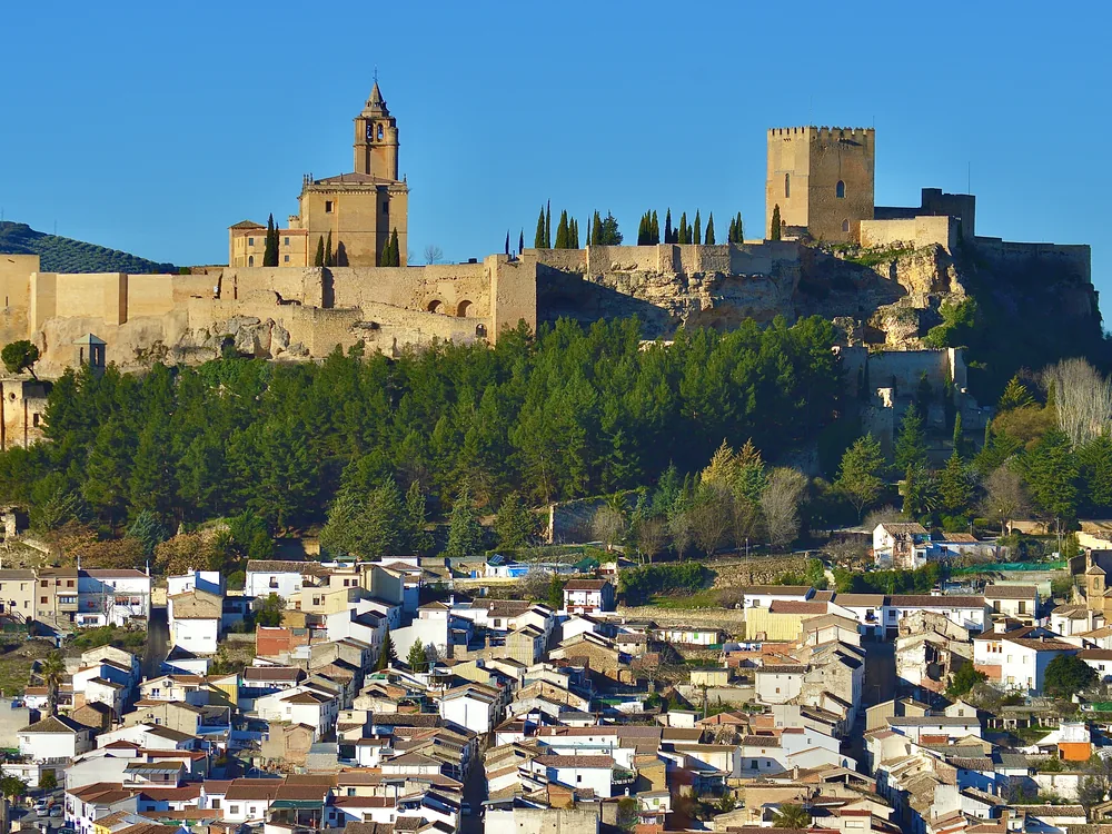 Fortaleza de la Mota on its hilltop above Alcalá la Real, Jaén province — the Nasrid fortified medina with the Mocha Tower rising above the medieval walls against the Andalusian olive-country skyline