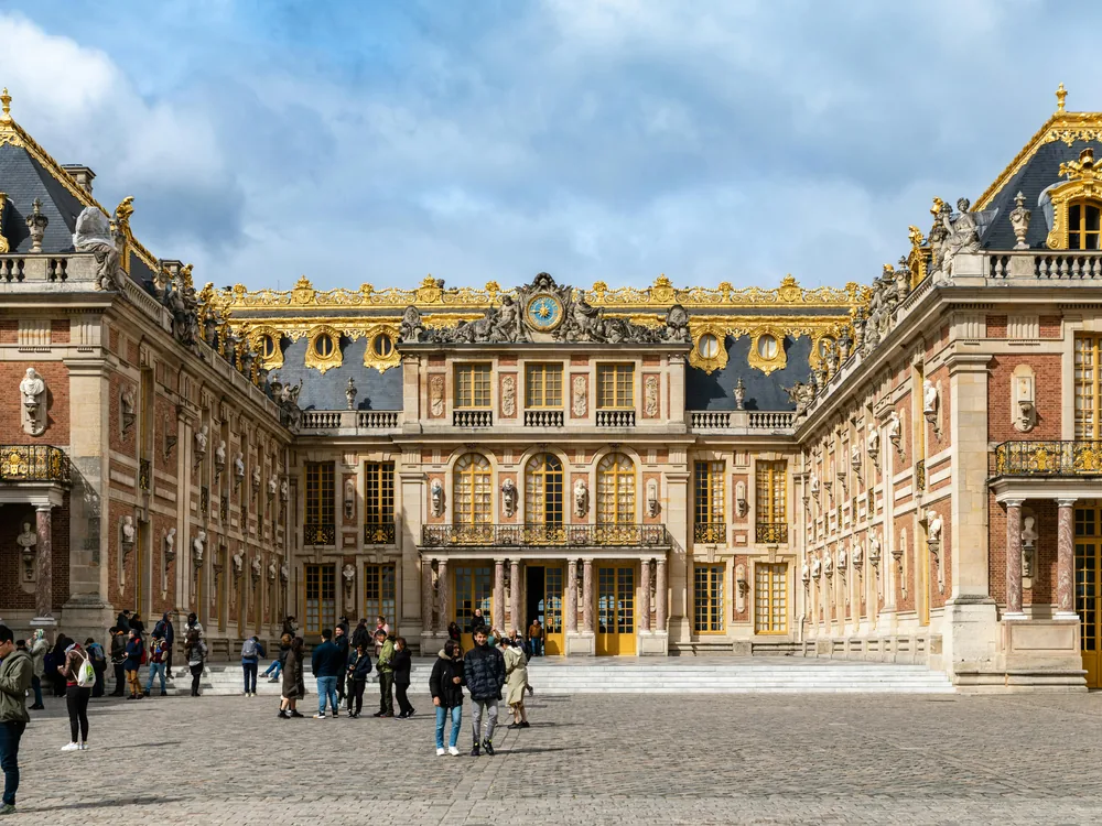 The Palace of Versailles garden facade reflected in the ornamental canal at golden hour