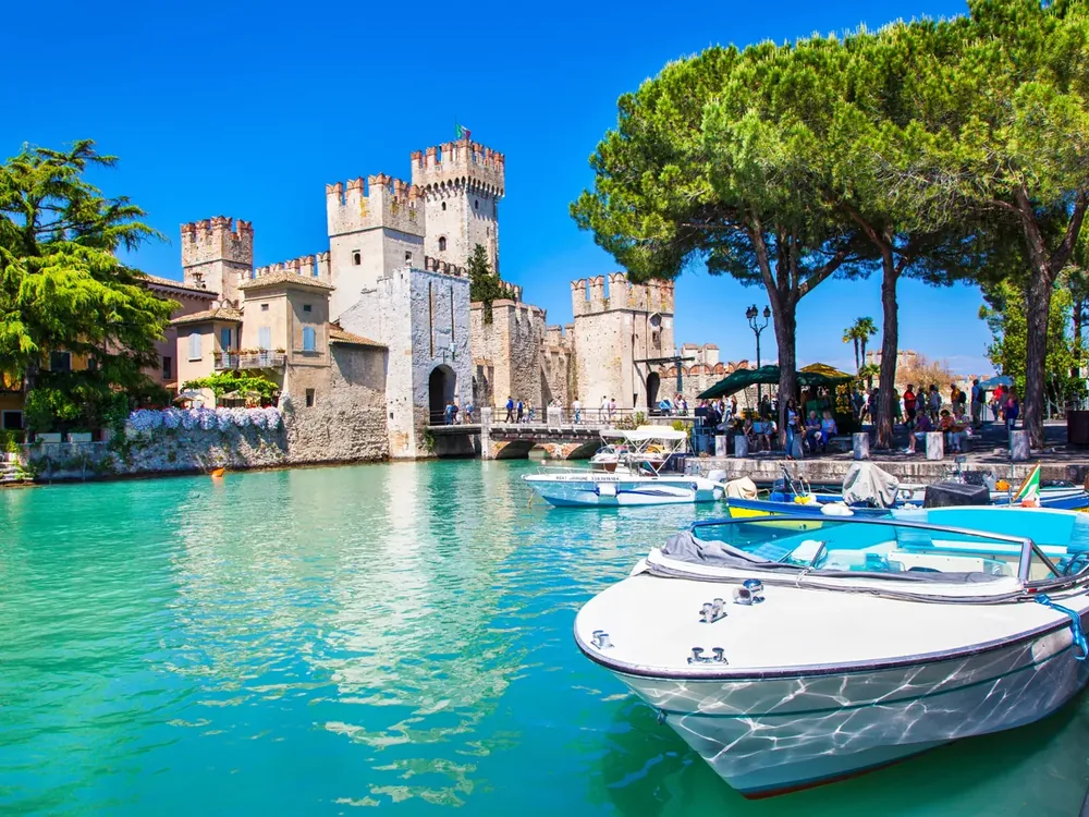 Lake Garda panorama with medieval tower and crystal-clear water
