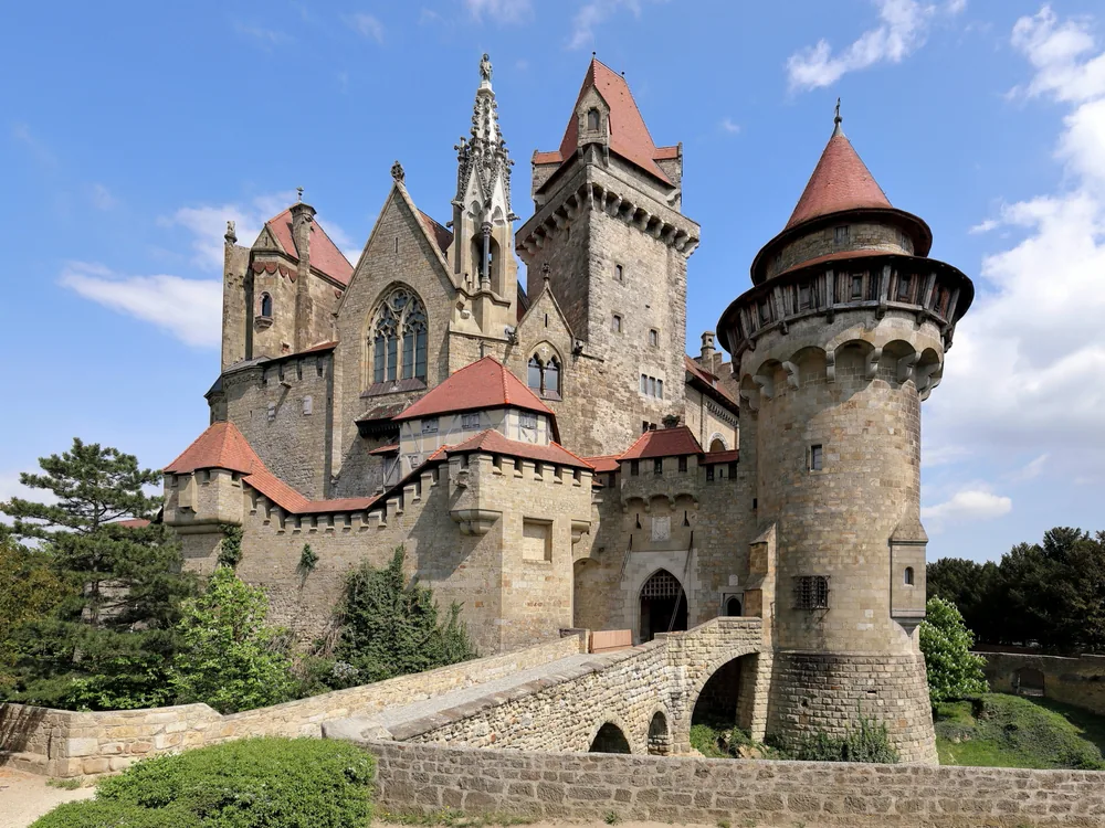 Kreuzenstein Castle perched on its forested hill north of Vienna, a neo-medieval 19th-century reconstruction rising above the Leiser Berge